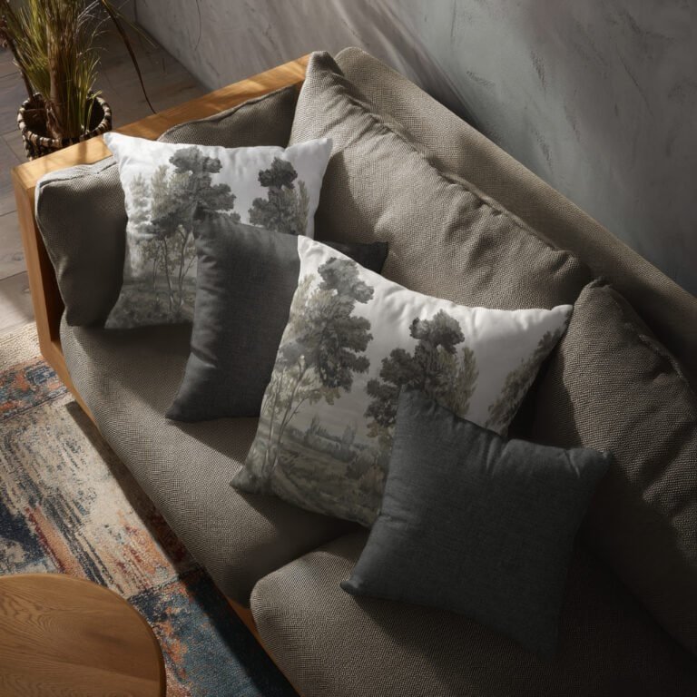 Almohadones decorativos con estampado de árboles en tonos verdes sobre sofá gris - Alchemyst